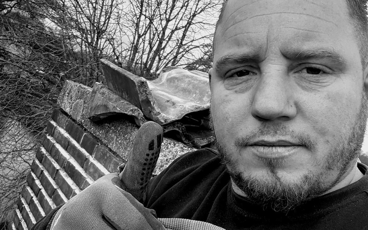 Leonard Jansen op een dak in Arnhem, naast losgeraakte dakpannen